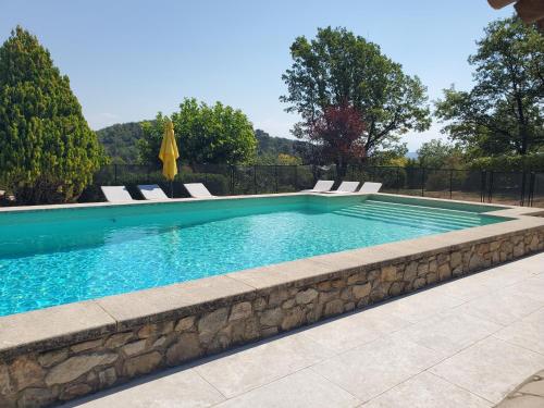 a swimming pool with chairs and a stone wall at Le Jas des Cannebieres in Villeneuve