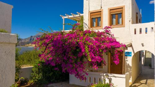 a building with purple flowers on the side of it at Akrotiri Apartments in Makry Gialos