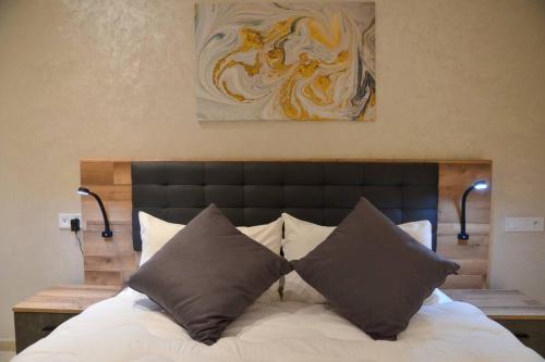 uma cama com duas almofadas e um quadro na parede em Sumptuous Appartement Y&M em Marrakech