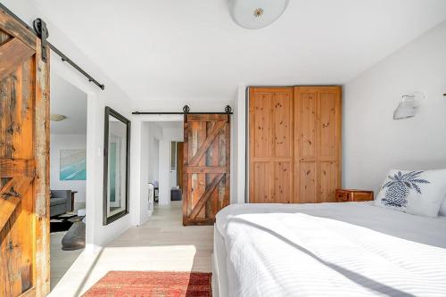 um quarto com uma cama branca e uma porta de madeira em The Edward at Bondi - A Blissful Beachside Retreat em Sydney