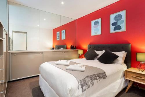 - une chambre avec un grand lit et un mur rouge dans l'établissement Ultra modern Inner-city Lifestyle in Darlinghurst, à Sydney