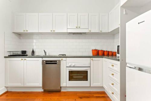 una cucina con armadietti bianchi e lavastoviglie in acciaio inossidabile di 'Four Keeps' A Cosy North Sydney Wharf Hideaway a Sydney