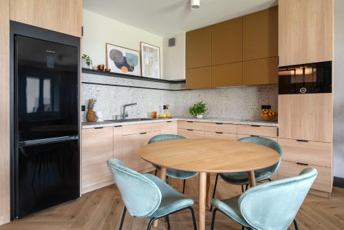 a kitchen with a wooden table and blue chairs at Apartament SezamkowaSKC in Skierniewice