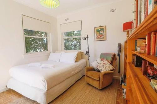 - une chambre avec un lit, une chaise et deux fenêtres dans l'établissement Art Deco at Marouba Beach - Soak up the Sand & Surf, à Sydney