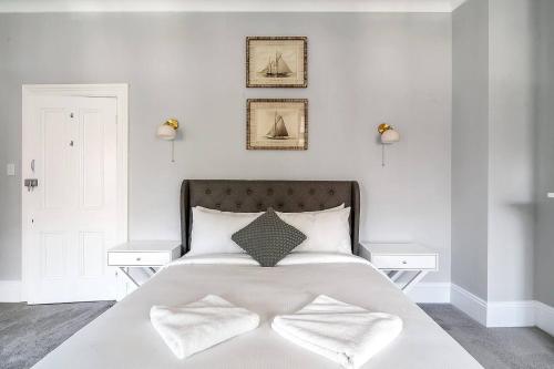 a white bedroom with a large white bed with two white tables at Kerridge Terrace - Old World Inner city Charm in Sydney