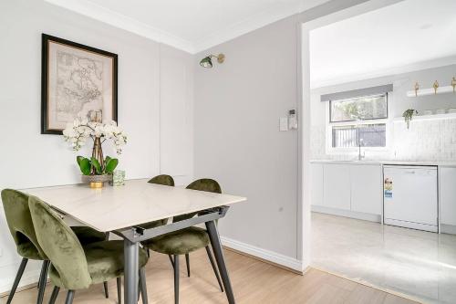 a white dining room with a table and chairs at Kerridge Terrace - Old World Inner city Charm in Sydney