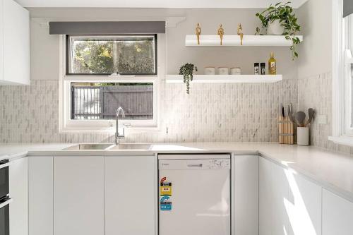 a white kitchen with a sink and a dishwasher at Kerridge Terrace - Old World Inner city Charm in Sydney
