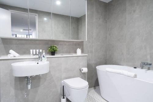 een badkamer met een wastafel, een toilet en een bad bij 'Eastgardens Splendour' Two-storey Style with Pool in Sydney