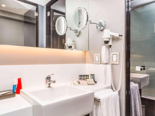 ein weißes Badezimmer mit einem Waschbecken und einem Spiegel in der Unterkunft Novotel Lima San Isidro in Lima