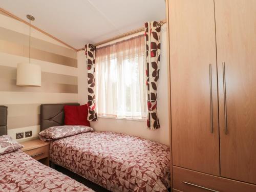 a small bedroom with two beds and a window at Swallows Lodge in Shepton Mallet