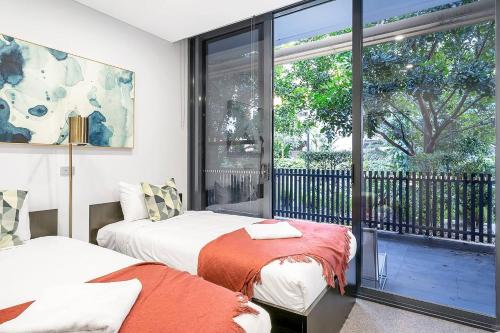 een slaapkamer met 2 bedden en een groot raam bij 'Eastgardens Splendour' Two-storey Style with Pool in Sydney