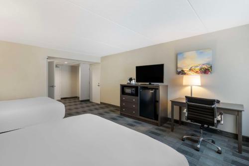 a hotel room with a bed and a desk and a television at Best Western Plus Alexandria Fort Belvoir in Alexandria