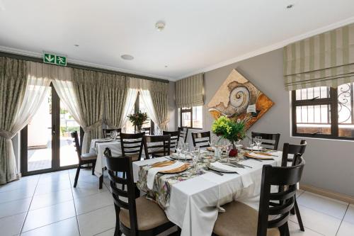 uma sala de jantar com uma mesa longa e cadeiras em The African Penguin Guesthouse em Pretoria