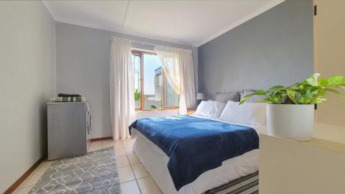 a bedroom with a bed and a window with a potted plant at Paradise Beach Cottage in Jeffreys Bay