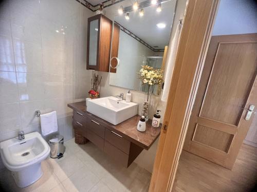 a bathroom with a sink and a toilet and a mirror at Los Sauces adosado a 10 minutos de Oviedo y 15 de Gijon in Llanera