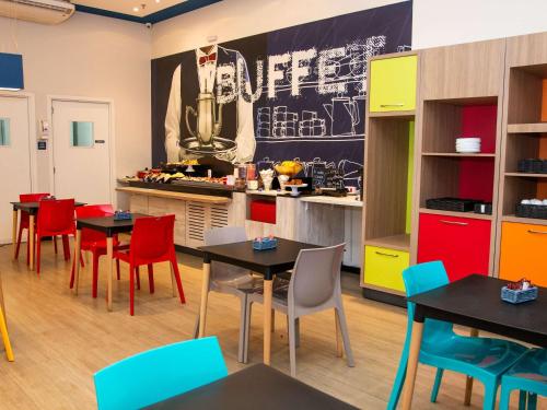 a restaurant with tables and chairs and a kitchen at ibis budget Itaperuna in Itaperuna