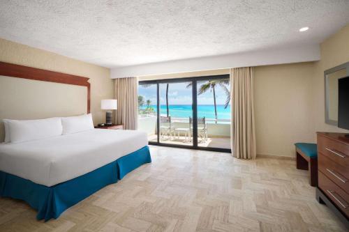 Wyndham Grand Cancun All Inclusive Resort & Villas في كانكون: غرفة نوم مع سرير وإطلالة على المحيط