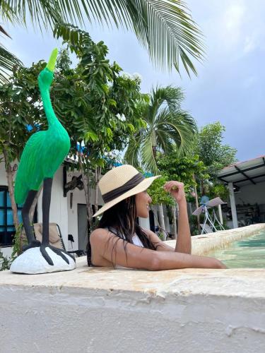 a woman in a hat sitting next to a statue of a bird at Casa Torices Real 12 in Cartagena de Indias