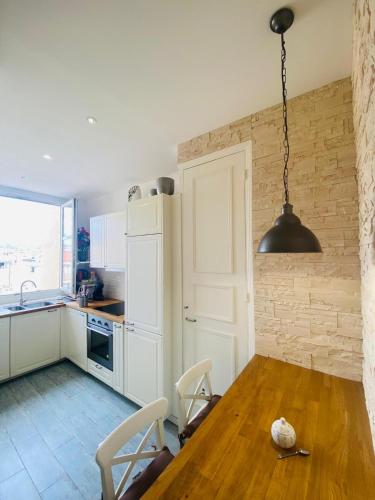 une cuisine avec une table en bois et un éclairage tamisé dans l'établissement Promenade des Anglais /Carré d'or - 2 mins plages, à Nice