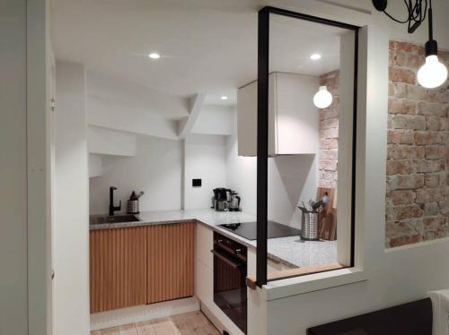 a kitchen with white cabinets and a brick wall at Sentral leilighet i Stavanger in Stavanger