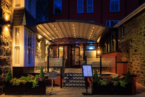 a building with awning over a patio at night at The Fanny Talbot in Barmouth