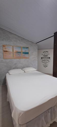 a large white bed in a room with three pictures on the wall at KITNET vila do Abraão in Abraão