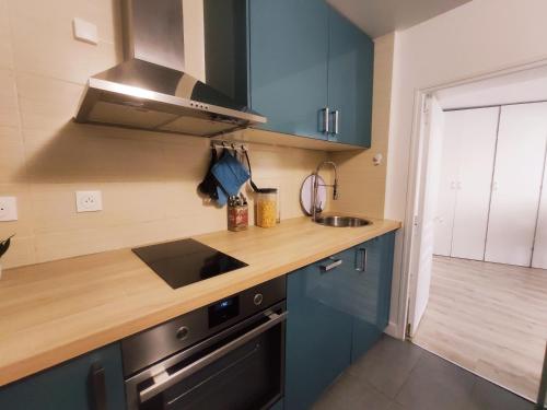 a kitchen with blue cabinets and a wooden counter top at Cosy Appartement 4P proche 12eme/Vincennes in Charenton-le-Pont