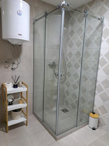La salle de bains est pourvue d'une douche avec une porte en verre. dans l'établissement Stan na danS Šid, à Šid