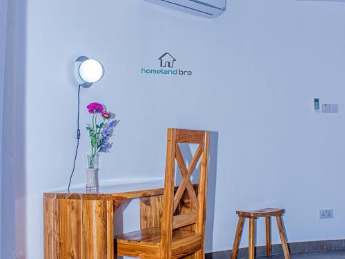 a table with a chair and a vase with flowers at homeland bro in Dar es Salaam