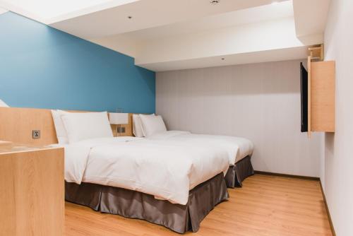 a bedroom with two beds and a blue wall at Hej Taipei in Taipei