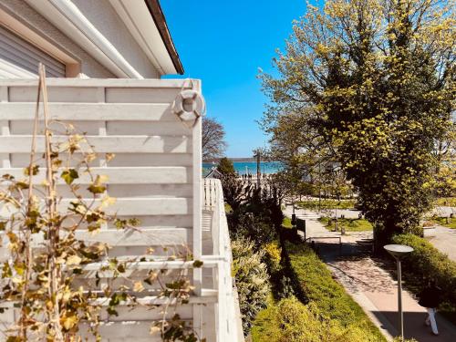 a white fence next to a house with the ocean in the background at Strand Studio mit Meerblick & Balkon in Lübeck
