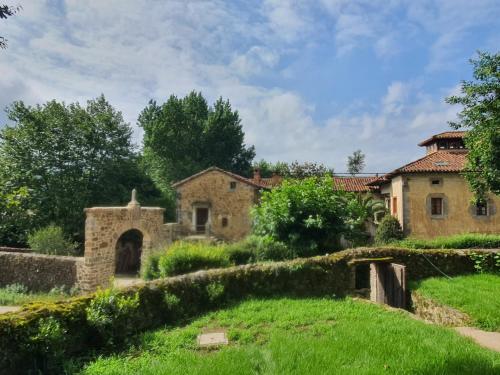 una antigua casa de piedra con una valla de piedra y un patio en LA CASA DEL HORNO, en Hornedo