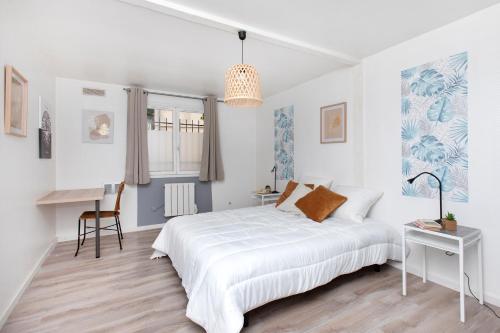 a white bedroom with a bed and a desk at La Risle - Appartement spacieux in Brionne