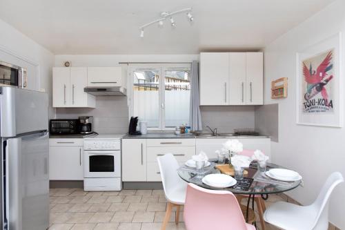 una cocina con armarios blancos y una mesa con sillas. en La Risle - Appartement spacieux, en Brionne