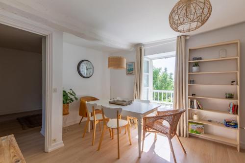 une salle à manger avec une table, des chaises et une horloge dans l'établissement Lyrique - Grand Appt 2 chambres, à Manvieux