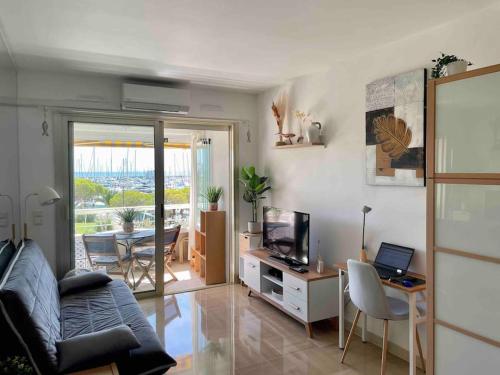een woonkamer met een bank en een tafel met een laptop bij Studio Port Marina in Villeneuve-Loubet