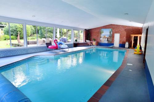 a large swimming pool in a large room with windows at Luxury property - Swimming Pool, Outdoor Kitchen, Games Room & Hot Tub in Usk