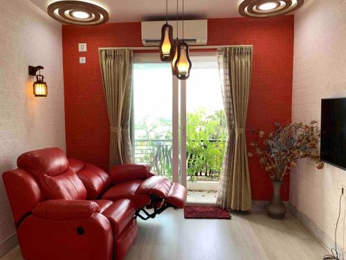 sala de estar de color rojo con sofá rojo y ventana en Luxury 3BHK Aprtmnt City View Balcony HSpeed Wifi Free Parking en Calcuta
