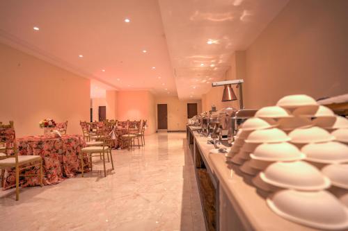 グレーター・ノイダにあるStiltstay Hotel, Greater Noidaの白い皿、テーブル、椅子が備わる宴会場