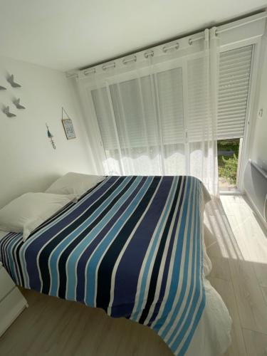 une chambre avec un lit avec une couverture rayée bleue et blanche dans l'établissement Entre bassin et forêt, à La Teste-de-Buch