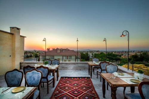 a restaurant with tables and chairs on a balcony with the sunset at Cappadocia Pyramid Stone House in Uchisar