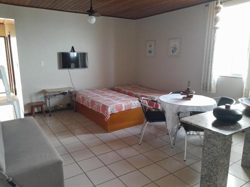 a bedroom with a bed and a table and a table and chairs at Apartamento com vista para o mar em Setiba Guarapari in Guarapari