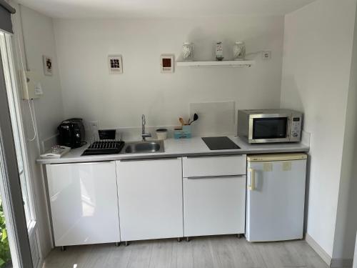 une cuisine blanche avec un évier et un micro-ondes dans l'établissement Entre bassin et forêt, à La Teste-de-Buch