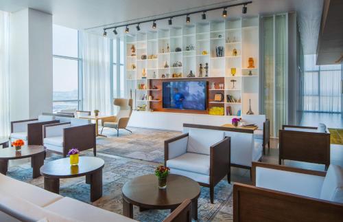 a hotel lobby with tables and chairs and a tv at Prima Link Hotel in Petaẖ Tiqwa