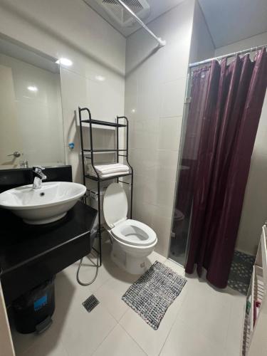 a bathroom with a toilet and a sink and a shower at One Palmtree Villas Airport Condo in Manila