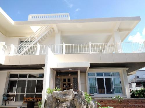 a white house with a balcony on top of it at フェーヌカジ洋室 in Miyako-jima