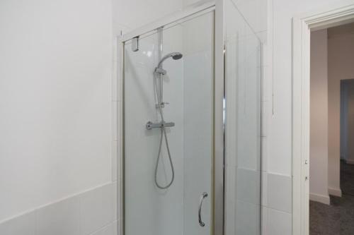 a shower in a bathroom with a glass door at Warm & Inviting 4-Bed on Church Road, Sleeps 4 in Stockton-on-Tees