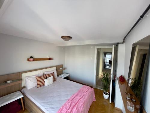 a small bedroom with a bed with a pink blanket at Central Izmir Delight: Cozy Alsancak Apartment in Konak