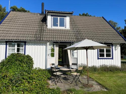 een wit huis met een tafel en een paraplu bij Stuga i Vomb in Veberöd