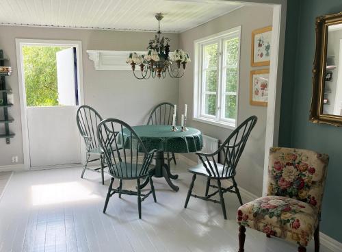 a dining room with a green table and chairs at Stuga i Vomb in Veberöd
